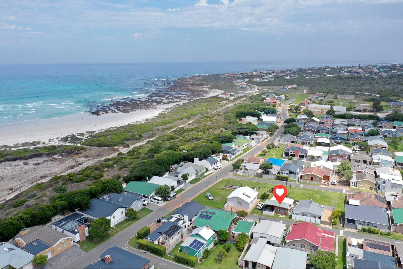 Aerial view of Pearly Beach Resort with Galjoen Gat cottage among the dune-side homes
