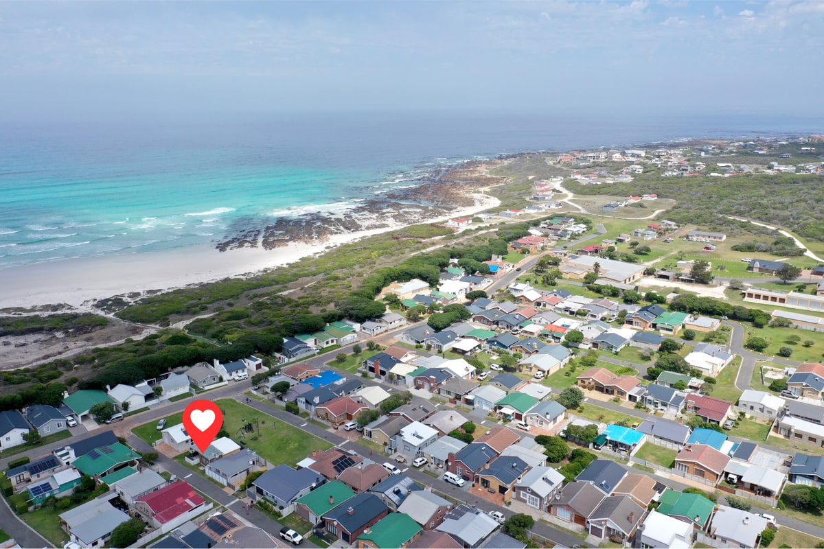 Wide aerial of the Pearly Beach coastline with Galjoen Gat cottage marked, showing the rocky shore and white-sand stretch