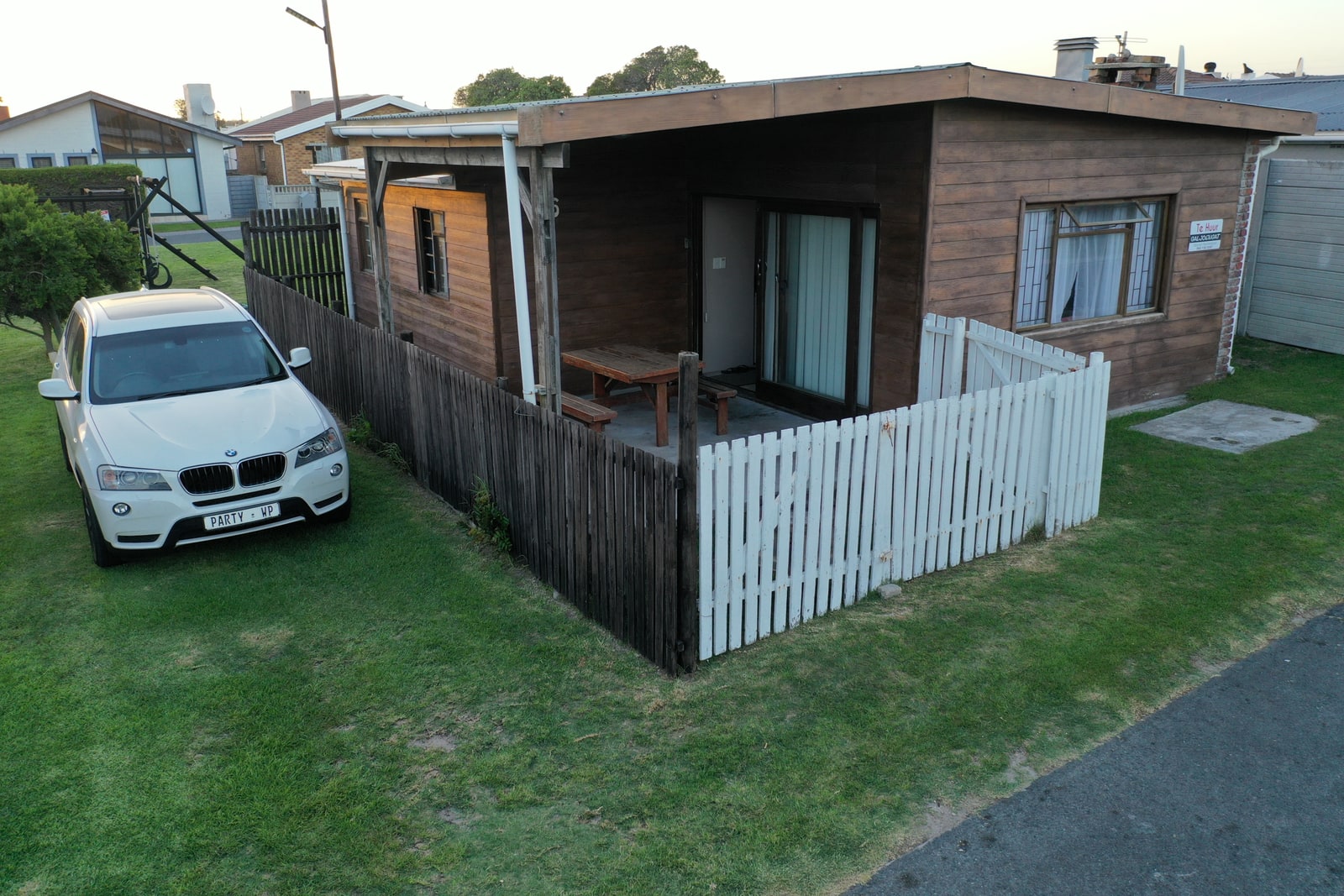 Galjoen Gat cottage exterior with parking for two cars, white picket fence, and outdoor patio area